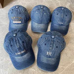 Collection of vintage washed denim baseball caps with various embroidery on stone background