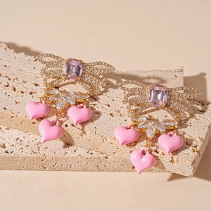 Pink heart drop earrings with bow design and zircon stones in a gold finish setting