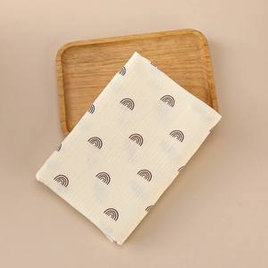 Muslin baby swaddle blanket with brown rainbow print on beige cotton fabric tray