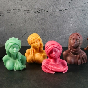 Artistic female bust goddess candles in four matte colors on a textured dark background
