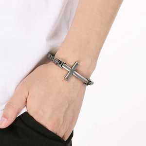 Detailed view of vintage silver cross bracelet with woven metal chain on wrist