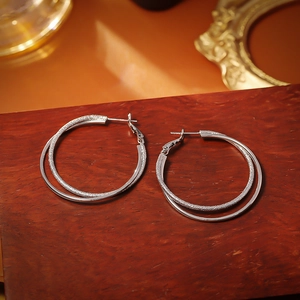 Creative silver double-layer hoop earrings with polished and frosted finish on wood base