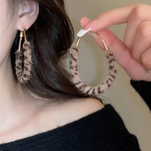 Gros plan de boucles d'oreilles créoles léopard en fausse fourrure et métal doré