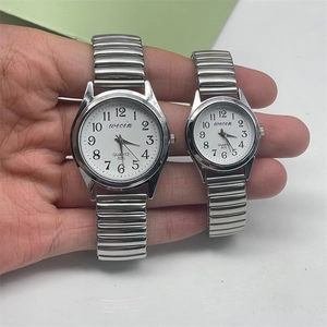 Close-up of a pair of silver quartz watches with elastic bands and large Arabic numerals