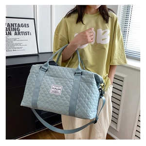 Detail of light blue quilted travel bag with adjustable strap and diamond stitching
