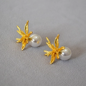 Macro shot of gold-plated organic flower earrings with elegant white pearl details