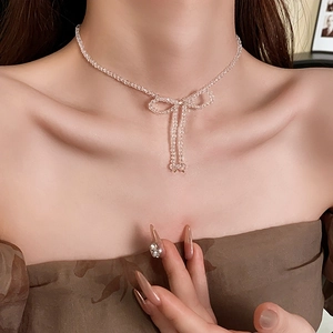 Close-up of a delicate beaded bow necklace with transparent crystals on a model neck