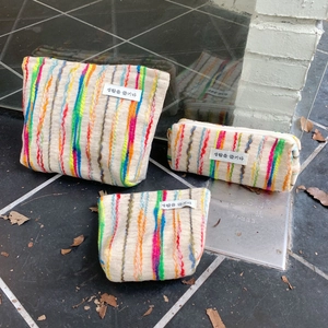 Three-piece set of knitted organizer bags with colorful vertical stripes and woven labels