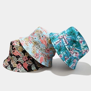 Three bucket hats featuring pink flamingos and tropical leaves in black, blue, and green