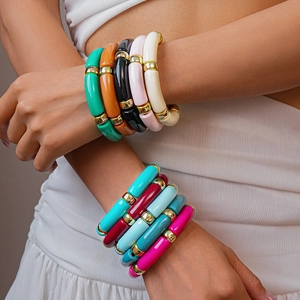 Braccialetti impilabili in acrilico a forma di bambù con sfere dorate al polso femminile