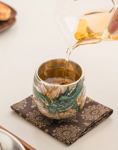 Macro shot of tea pouring into a high-end silver-plated tea cup with a green dragon relief