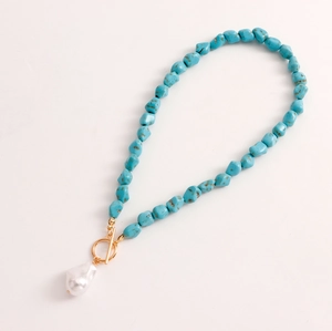 Detail of turquoise beads with golden toggle clasp and white baroque pearl pendant
