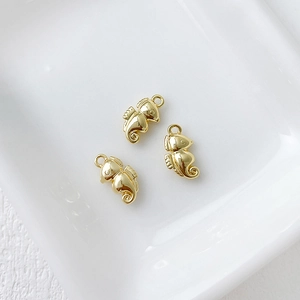 Detailed macro view of three 14k gold-plated seahorse pendants on white ceramic