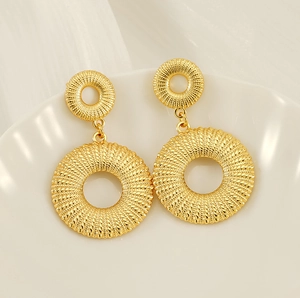 Close-up of 18K gold titanium steel earrings with woven texture on white tray
