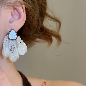 Detail of seashell and pearl tassel earring with water drop pendant on ear