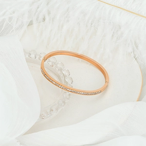 Detail of rose gold bangle with pave-set zircons on white feathers and stone tray