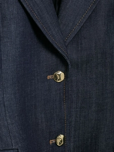 Dettaglio della giacca di jeans blu scuro con bottoni in metallo dorato e cuciture marroni
