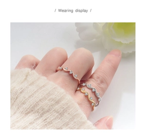 Close-up of wavy zircon ring worn on finger in rose gold, gold and silver tones