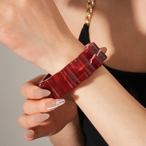 Close-up of wide burgundy resin bangle with marble texture on female wrist