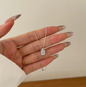 Detail of silver S925 necklace with rectangular ice-flower cut zircon pendant on hand