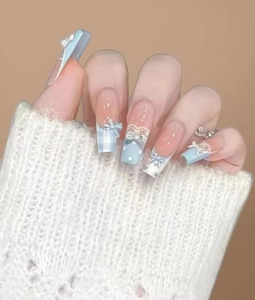 Détails des faux ongles bleu clair avec nœuds 3D, perles et motifs en dentelle