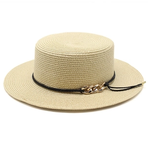 Détail d'un chapeau de paille beige avec ruban en corde noire et boucle de chaîne dorée