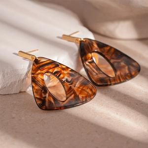 Detail of amber resin triangle earrings with retro hollow design and gold metal posts