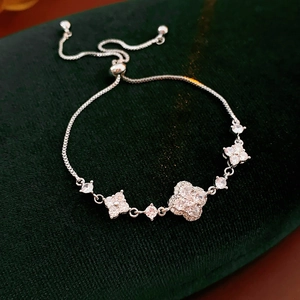 Detailed view of silver flower charms with white zircons on a green velvet surface