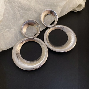 Detailed close-up of silver geometric hoop earrings with textured sunburst metal finish