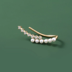 Detailed close-up of golden ear cuff with sparkling zircons and elegant white pearls