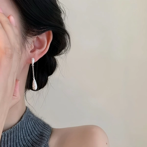 Close-up of sparkling zircon teardrop earrings with elegant tassel on a model