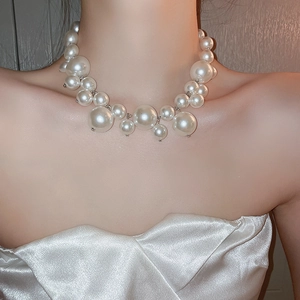 Close-up of irregular white pearl cluster necklace shown on model for detailed texture