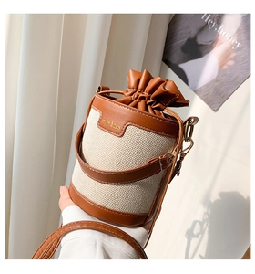 Detail of fabric and leather stitching on bucket bag with drawstring closure and strap