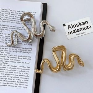 Close-up of elegant gold and silver snake-shaped metal hair claws on vintage books