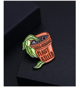 Détail de la broche plante verte avec texte Well-Meaning Plant Killer sur le pot orange