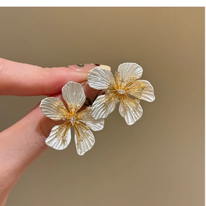 Detailed macro view of bimetal flower stud earrings with shimmering zircon centers