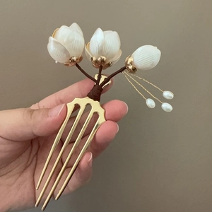 Détail du peigne à cheveux magnolia blanc avec dents dorées et glands en perles