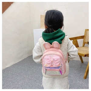 Rear view of pink kids backpack with rabbit ears, sequins, and a large bow on a child