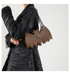Detailed view of brown bat-shaped gothic shoulder bag with silver skull and chain strap