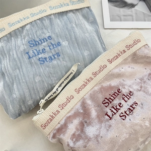 Detail of velvet makeup bags with 'Shine Like the Stars' embroidery and metal zippers