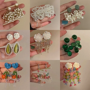 Macro display of nine trendy flower pearl earrings with crystals and beaded tassels