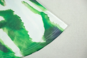 Detail view of double-stitched hem and green ink-print pattern on breathable fabric