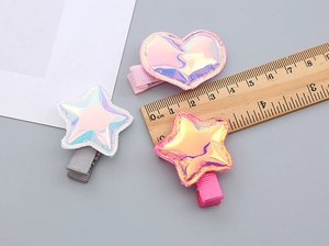 Detailed view of colorful star and heart hair clips with a wooden ruler for sizing