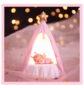 Detail of a pink tent night light with a sleeping baby angel and gold star top decoration