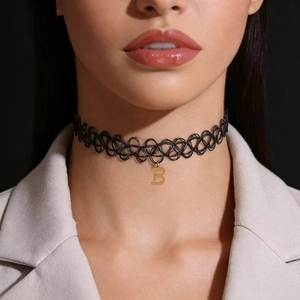 Close-up detail of a black fishline tattoo choker with a gold-tone letter B pendant.