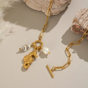 18K gold seahorse necklace with white pearl and shell charms on beige background