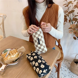 Detailed corduroy pouch showing vintage check and floral patterns in a café setting