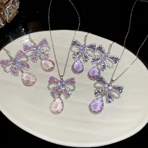 Butterfly pendant necklace and earrings set with purple gradient zircons on a white tray