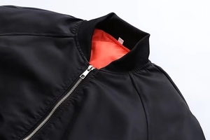 Detail der schwarzen Bomberjacke mit silbernem Reißverschluss und orangefarbenem Futter