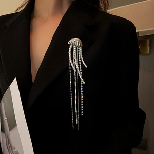 Close-up of a silver jellyfish brooch with pearl and rhinestone tassels on a black blazer
